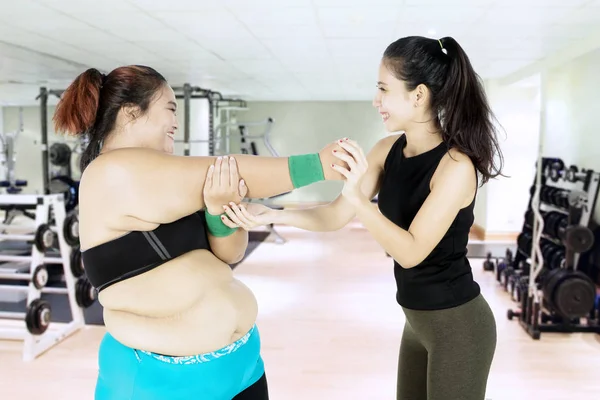 Fat woman doing stretch with her personal trainer — Stock Photo, Image