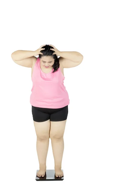Разочарованная толстая женщина стоит на весах — стоковое фото