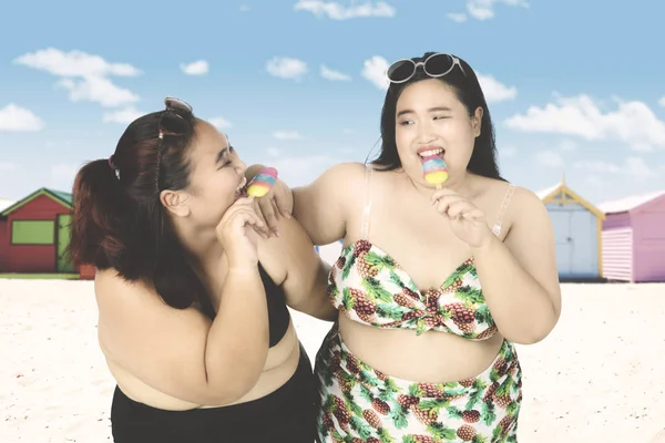 Obese women eat ice cream at shore — Stock Photo, Image