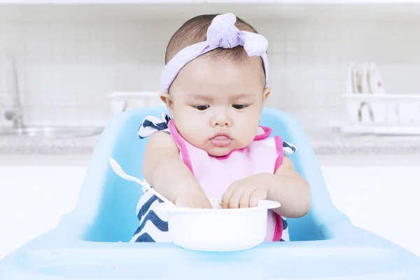 Doce bebê comendo com tigela na cadeira — Fotografia de Stock