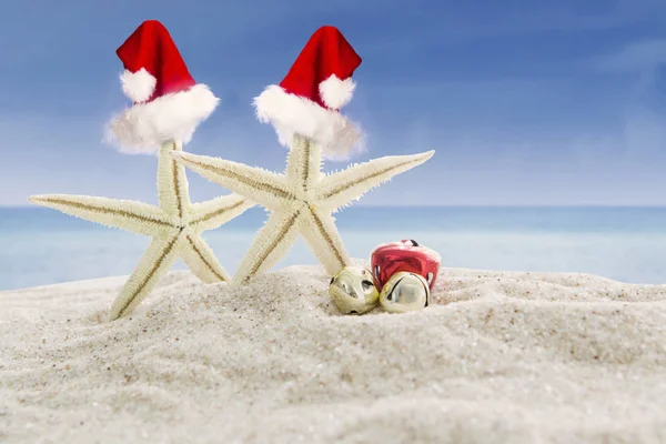 Två starfishes med Santa hattar på stranden — Stockfoto