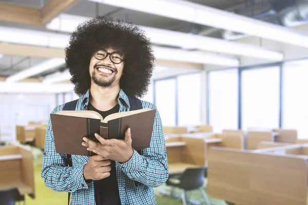 Молодой студент улыбается с книгой в классе — стоковое фото
