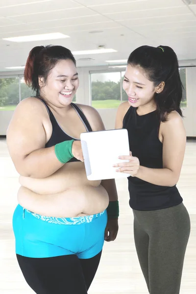 Fat woman and instructor smiling at digital tablet — Stock Photo, Image