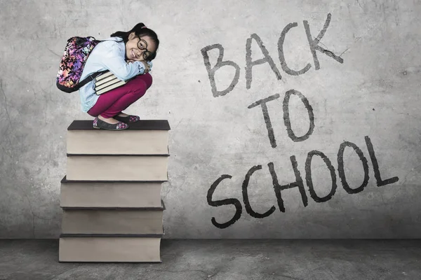 Little girl squat on textbooks — Stock Photo, Image