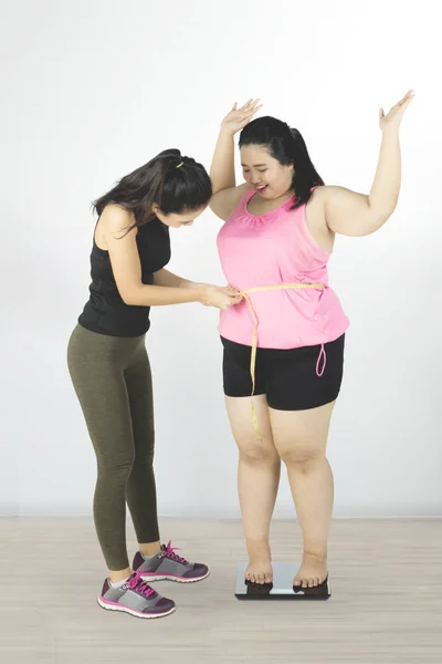 Trainer measuring belly of fat woman — Stock Photo, Image