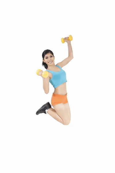 Woman holds dumbbells and jump — Stock Photo, Image