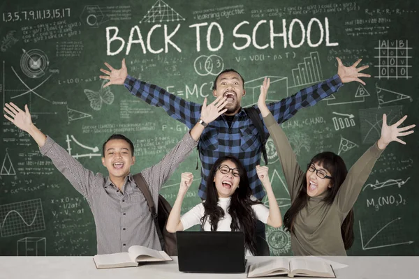 Cheerful students with scribble on blackboard — Stock Photo, Image