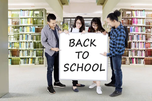 Одноклассники хранят текст "Назад в школу" — стоковое фото