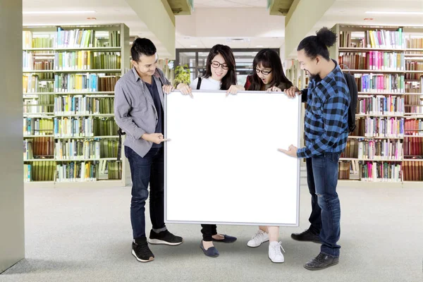 Les étudiants du collège tiennent tableau blanc dans la bibliothèque — Photo