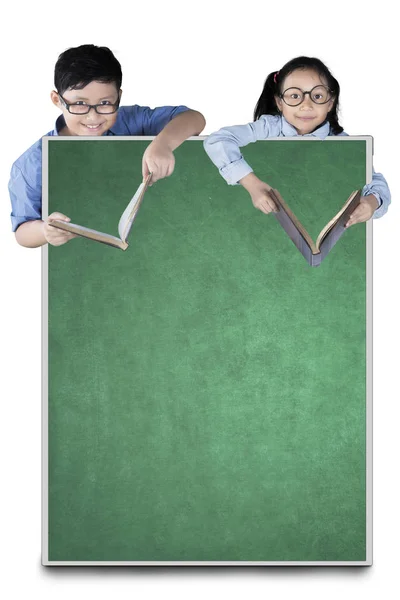 Estudiantes de primaria sosteniendo libro con pizarra — Foto de Stock