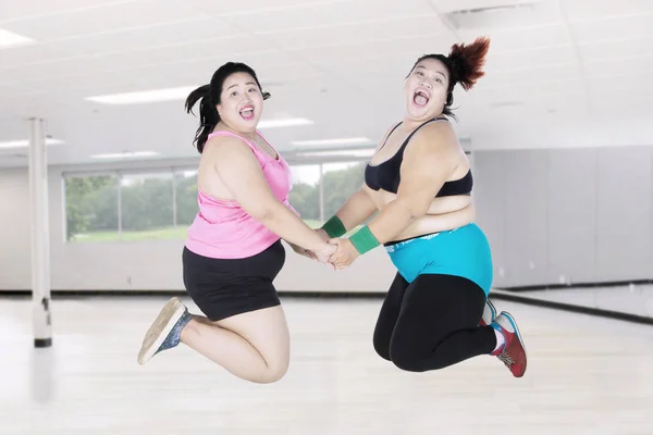 Obese women leaping together in gym