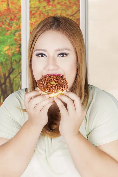 Feta kvinnan äter donut — Stockfoto