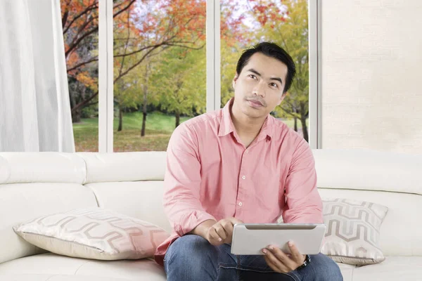 Nachdenklicher Mensch nutzt Tablet auf der Couch — Stockfoto