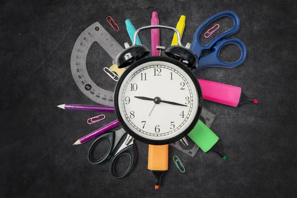 Fournitures scolaires avec horloge sur le tableau noir — Photo
