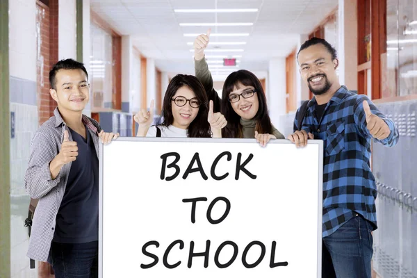 Étudiants avec texte de retour à l'école à bord — Photo