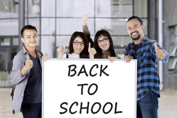 Los estudiantes sostienen la junta con el texto de regreso a la escuela — Foto de Stock