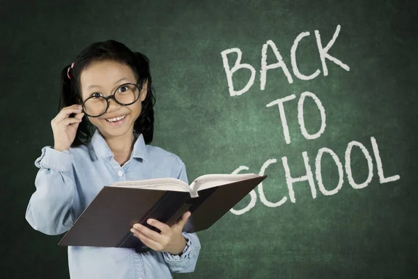 Schoolgirl with back to school word on chalkboard — Stock Photo, Image
