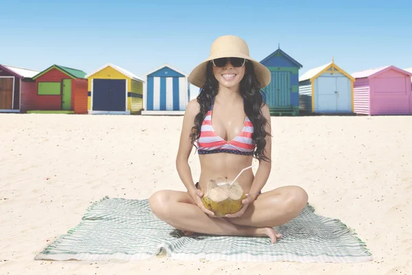 Жінка п'є кокосову воду на пляжі — стокове фото
