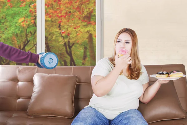 Mulher recusa haltere e come donuts — Fotografia de Stock