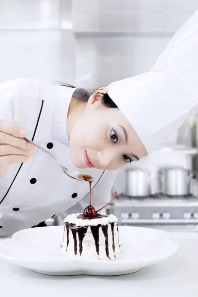 Prachtige vrouwelijke chef-kok siert een taart — Stockfoto