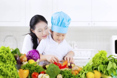 Çocuk mutfakta sebze kesmek öğrenir