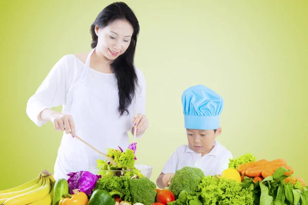 Menino e mãe preparando salada — Fotografia de Stock