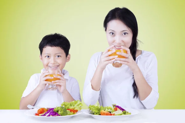 Boy with mother eat salad and drink juice — Stock Photo, Image