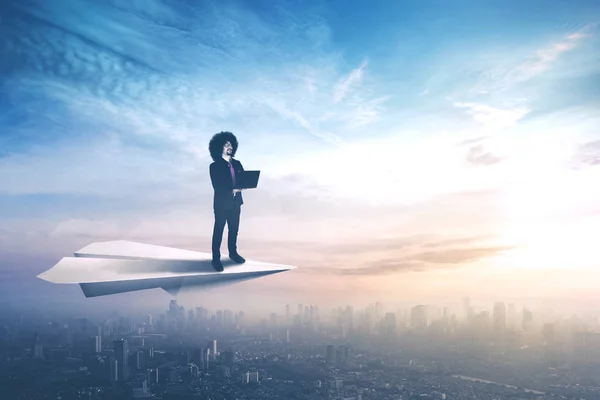 Businessman using laptop on paper plane — Stock Photo, Image