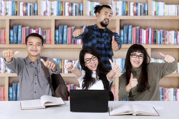 Diversidade estudantes com polegares para cima na biblioteca — Fotografia de Stock