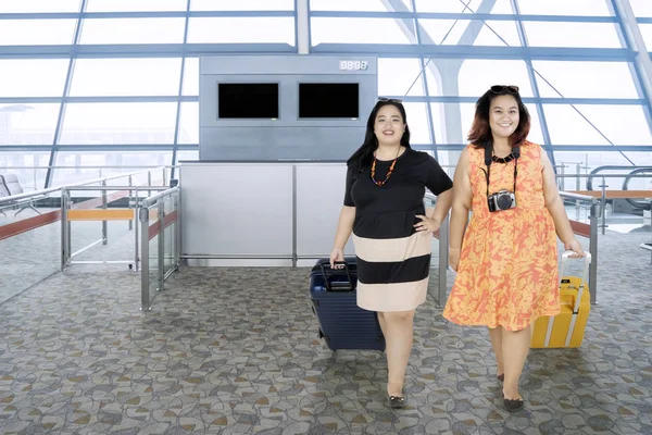 Толстые женщины, гуляющие в терминале аэропорта — стоковое фото
