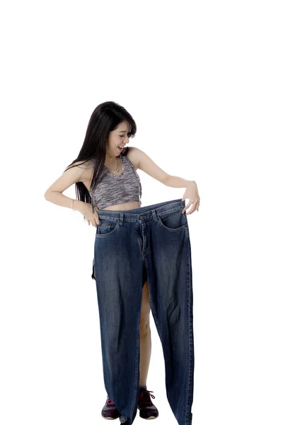 Happy Chinese woman holds old jeans — Stock Photo, Image