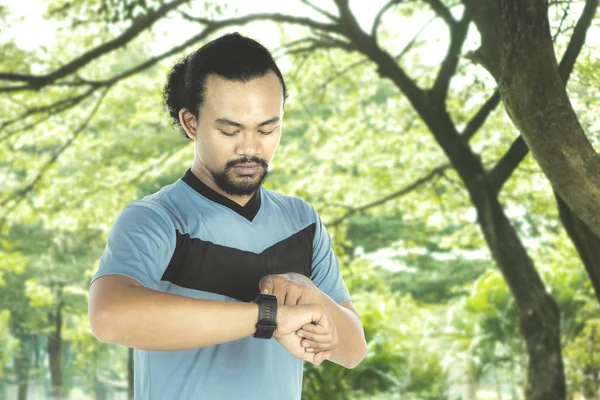 Frisk människa tittar på smartwatch på park — Stockfoto