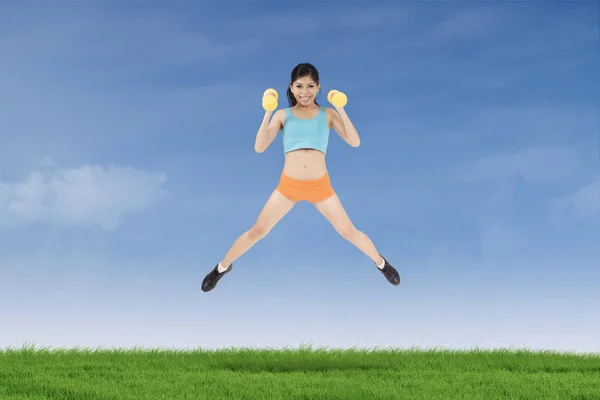 Здоровая женщина прыгает с гантелями — стоковое фото
