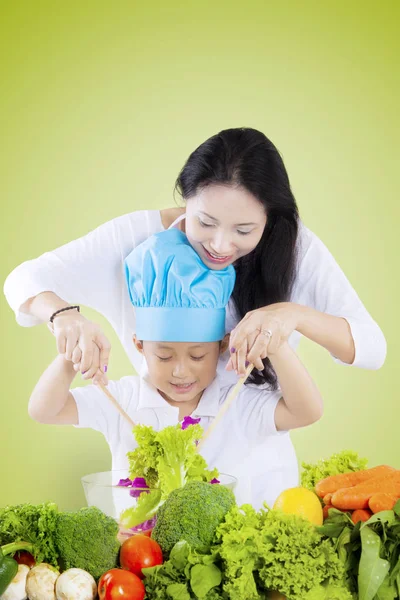 Мама помогает сыну делать салат. — стоковое фото