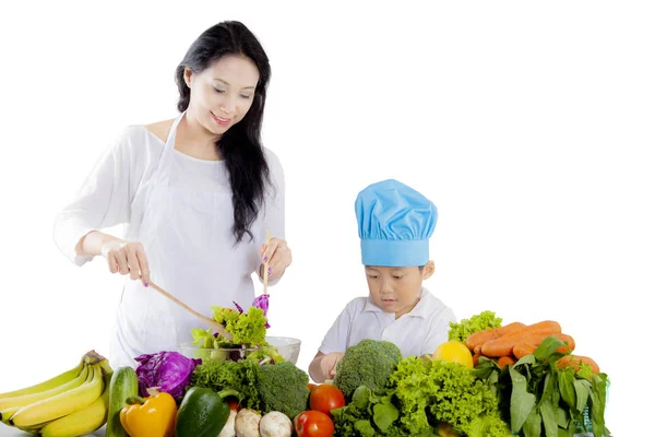 Hübsche Mutter mit ihrem Sohn, der einen Salat zubereitet — Stockfoto