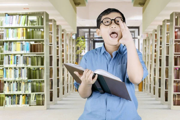 Schoolboy shouting while holding a textbook — Stock Photo, Image