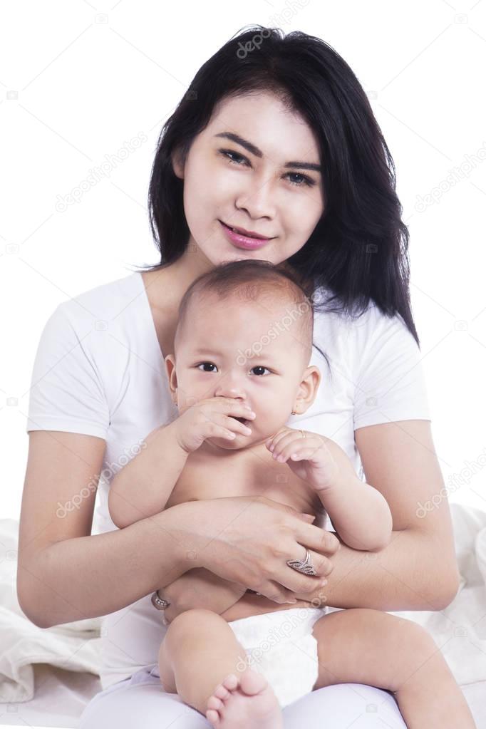 Pretty mother hugging her baby on studio