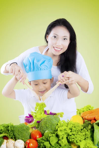 Donna e bambino mescolando insalata — Foto Stock