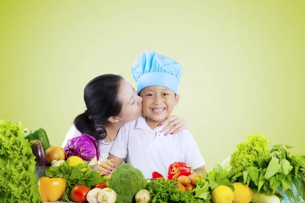 女性のテーブルの上の野菜と息子をキスします。 — ストック写真