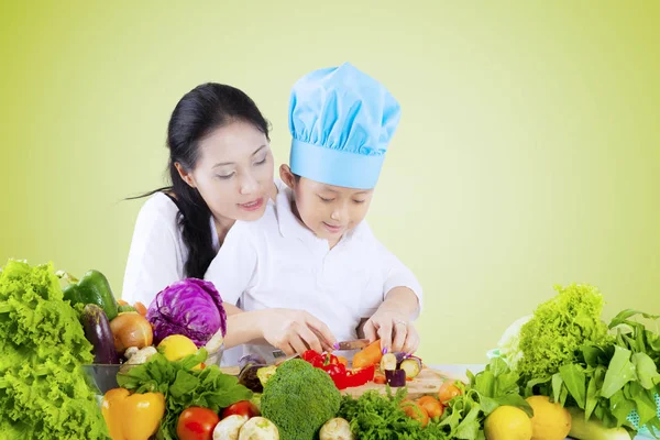 Woman teaches her child to cut vegetables — Stock Photo, Image