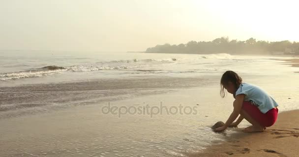Девушка играет песок в одиночку на пляже — стоковое видео