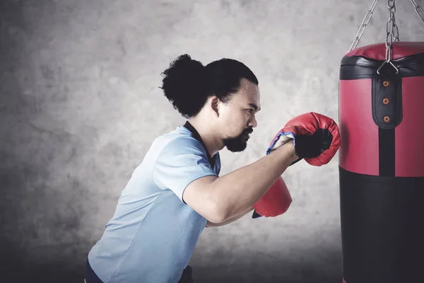 Afro man punching a boxing sack — Stock Photo, Image