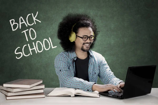 Afro estudante usa um laptop e ouvir música — Fotografia de Stock