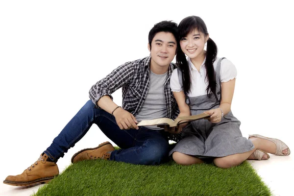 Aziatische studenten met boek op gras — Stockfoto