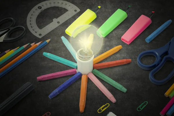 Bright bulb with stationery on the blackboard — Stock Photo, Image