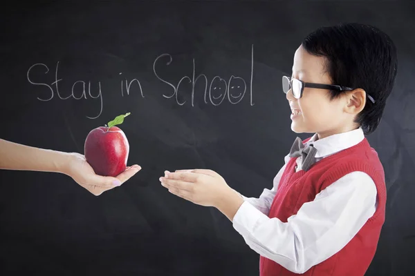 Дитина отримує червоне яблуко в класі — стокове фото