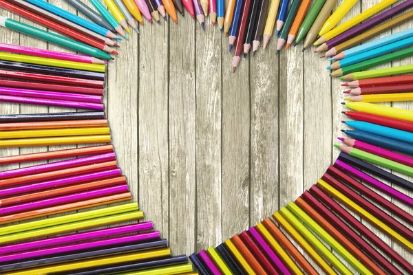 Цветные карандаши в форме знака любви на столе — стоковое фото