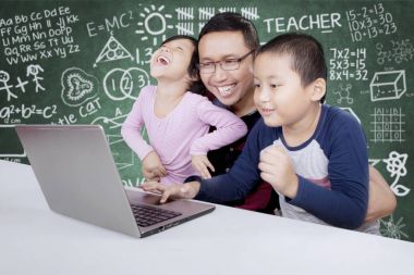 İlköğretim öğrencilerinin öğretmenleri ile bir dizüstü bilgisayar kullanarak