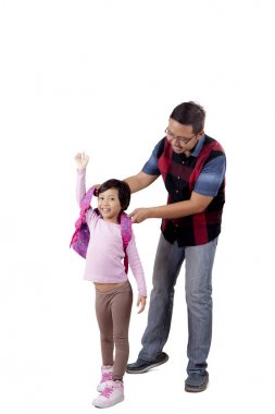 Babası onun alt sırt çantası giymek için yardımcı olur.