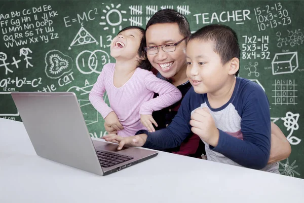 Alunos do ensino fundamental usando um laptop com seu professor — Fotografia de Stock